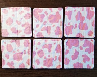 Può includere: Sei sottobicchieri in tessuto con stampa di mucca rosa e bianca. I sottobicchieri sono quadrati e hanno un design trapuntato.