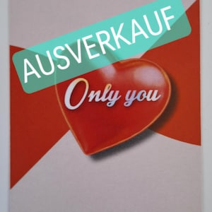May include: A rectangular card with a red heart and the words "Only you" in cursive. The heart is set against a red background, with the word "AUSVERKAUF" in a green banner across the top. The card has rounded corners.