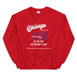 May include: A red sweatshirt with the word "Chicago" in white script. Below, a blue and white graphic of a van with the text "WETBANDITS.CO." and a phone number. The text "ASK FOR MARV & HARRY" is also visible.