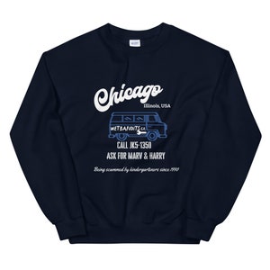 May include: Navy blue sweatshirt with a white graphic that says "Chicago" and "Illinois, USA". Below the text is a blue illustration of a van with the text "WETBANDITS CO." and "CALL JK5-1350 ASK FOR MARV & HARRY". The text "Being scammed by kindergarteners since 1990" is also included.