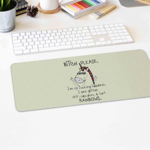 May include: A rectangular light green desk mat featuring a cartoon unicorn with a rainbow mane and a middle finger gesture. The mat has the text: "BITCH PLEASE, I'm so fucking fabulous, I pee glitter, shit cupcakes, & fart RAINBOWS."
