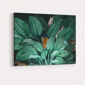 May include: A rectangular canvas wall art print featuring a dense cluster of large, dark green tropical leaves. A leopard face peeks through the centre foliage, while a zebra head and a patterned snake are partially visible among the greenery.