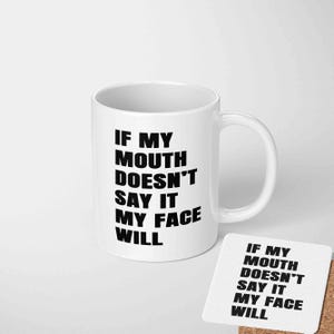 May include: A white ceramic mug and coaster set. Both the mug and coaster display the text "IF MY MOUTH DOESN'T SAY IT MY FACE WILL" in bold black lettering. The mug has a curved handle.