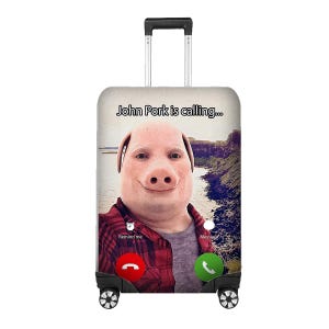 May include: A rolling suitcase with a novelty design. The suitcase has a pig face with the text "John Pork is calling..." and call buttons. The background shows a landscape with water and cliffs. It has a retractable handle and wheels.
