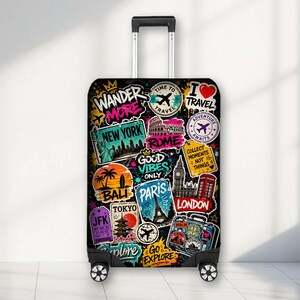 May include: A black rolling suitcase featuring a vibrant collage of travel-themed graphics, including the text Wander More, New York, Rome, Good Vibes Only, Paris, London, Tokyo, and Go Explore, alongside illustrations of landmarks and aeroplanes.