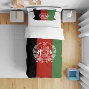 May include: Bedding set featuring the flag of Afghanistan. The set includes a duvet cover, pillowcase, and a white top sheet. The duvet cover has vertical black, red, and green stripes with the national emblem in the centre.
