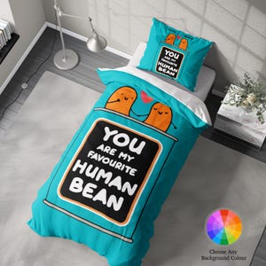 May include: A turquoise blue duvet cover featuring a cartoon image of two bean-shaped characters holding hands inside a can. The text on the can reads "You are my favourite human bean".