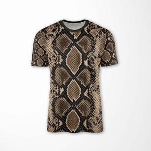 May include: A short-sleeved t-shirt featuring an all-over brown, tan, and black snakeskin print pattern. The garment has a round crew neckline with a dark brown trim and a straight hemline, displaying a realistic reptilian scale texture.