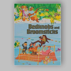 May include: A book cover titled Bedknobs and Broomsticks featuring a colourful illustration of a brass bed floating over water with three children and a man in a brown suit, surrounded by various cartoon animals and small colourful fish.