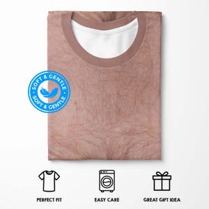 Puede incluir: Una camiseta doblada con un estampado realista de un pecho peludo. La camiseta tiene un cuello marr&oacute;n y un cuello interior blanco. La imagen incluye iconos de ajuste perfecto, f&aacute;cil cuidado y gran idea de regalo.