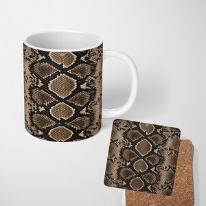 May include: A white ceramic mug and a square coaster, both featuring a repeating brown and black snakeskin pattern. The mug has a cylindrical body with a side handle, while the coaster has a cork backing visible at the bottom edge.