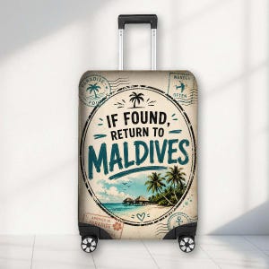 May include: A rolling suitcase with a beige cover featuring a circular graphic that reads IF FOUND, RETURN TO MALDIVES. The design includes palm trees, a beach, ocean, and travel-themed stamps with text like PARADISE FOUND and WANDER OFTEN.
