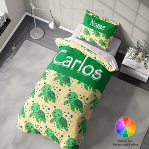 May include: A green and yellow turtle-themed bedding set with the name "Carlos". The duvet cover and pillowcase feature cartoon turtles and blue dots on a yellow background. The duvet cover has the name "Carlos" in large white letters.