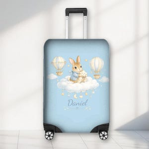 May include: A light blue suitcase with a watercolour design of a rabbit and teddy bear on a cloud, with hot air balloons and stars. The name "Daniel" is written below the cloud.