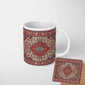 May include: A white ceramic mug and square coaster set. Both items display a detailed rug pattern in red, cream, and navy blue. The mug has a curved handle, and the coaster has a cork backing. The design is symmetrical and intricate.