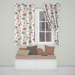 May include: White curtains featuring a repeating watercolour pattern of orange foxes, green trees, and brown mushrooms. The fabric drapes over a window frame, displaying a consistent woodland-themed print across the entire surface of the panels.