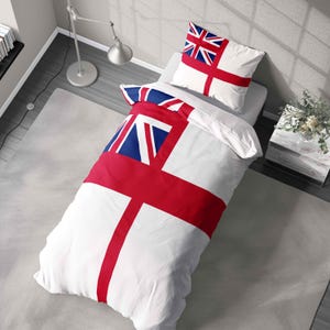 May include: A white duvet cover and pillowcase set with a bold red cross design and a blue and white emblem. The bedding is arranged on a bed, with a matching pillow. The design is reminiscent of a flag.