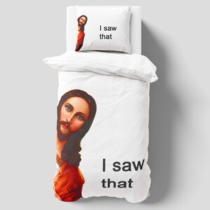 May include: White bedding set with a graphic of a person with long brown hair and a beard, wearing a red robe. The pillow has the text "I saw that". The duvet cover also has the text "I saw that".