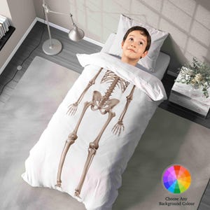 May include: A white duvet cover and pillow set with a detailed illustration of a human skeleton in shades of brown and beige. The image also includes a child's head peeking out from the top of the duvet. The text "Choose Any Background Colour" is visible.