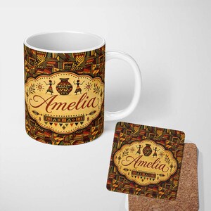 May include: A white ceramic mug and a square cork coaster featuring a repeating geometric pattern in shades of brown, yellow, and black. Both items display a central cream-coloured label with the name Amelia, a pot, and two figures.