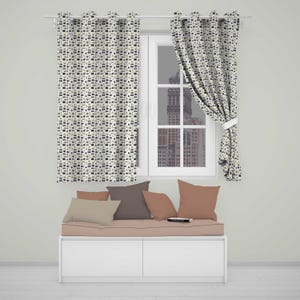 May include: Two off-white curtains with a repeating pattern of small black and grey camera icons hang on a rod. Below, a white bench features a seat cushion and four throw pillows in shades of muted pink, beige, and dark grey, arranged neatly.