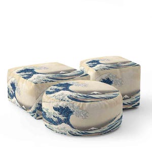 May include: Three ottomans with a Japanese wave design in blue and white. The ottomans are a cube, a rounded square, and a cylinder. The fabric has a cream background. The design is reminiscent of Hokusai's 'The Great Wave off Kanagawa'.
