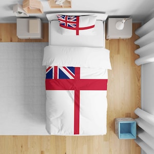 May include: White bedding set with a red cross design and a blue and white flag detail. The set includes a duvet cover and a pillowcase. The bedding is on a bed with a wooden floor, viewed from above.