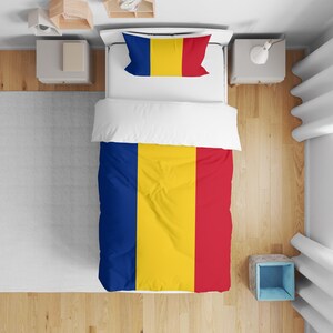 May include: Bedding set with the Romanian flag design. The duvet cover and pillowcase feature vertical stripes of blue, yellow, and red. The bedding is on a white bed with wooden flooring.