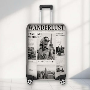 May include: A black and white suitcase featuring a newspaper-style print with the title WANDERLUST. The design includes a photograph of a person in a headscarf and trench coat, the Eiffel Tower, a handbag, and a New York City skyline graphic.