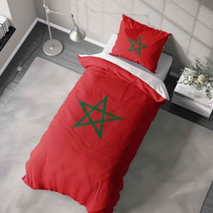 May include: A red duvet cover and pillowcase set with a green star design. The bedding is displayed on a bed with a white sheet. The design is a flag of Morocco.