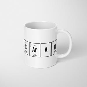 May include: White ceramic mug with a black design of the periodic table elements for the word "SARAH".