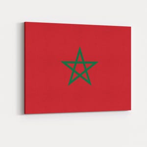 May include: A canvas print of the Moroccan flag. The flag has a red background with a green, five-pointed star in the centre. The rectangular canvas is mounted on a wooden frame, ready to hang.