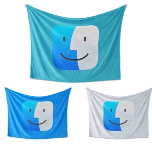 May include: Three rectangular wall tapestries featuring a smiling face design. The tapestries are in shades of blue and white. The design shows a blue and white face with a black smile and two black dots for eyes. The tapestries are suspended against a white backdrop.