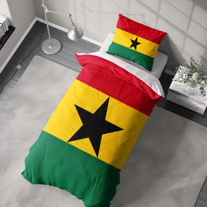 May include: A bed set with the Ghanaian flag design. The duvet cover and pillowcase feature the flag's colours: red, yellow, green, and a black star. The bedding is arranged on a bed, displaying the bold design.