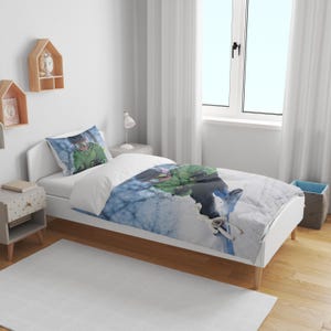 May include: A white twin-sized bed with a blue and white duvet cover featuring a snowboarder in a green jacket. The duvet cover has a white pillowcase with a snowboarder in a green jacket.