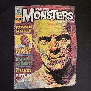 Peut inclure: Une couverture de bande dessinée vintage représentant un gros plan du visage d'un monstre. La couverture est jaune, rouge et noire avec le titre "Famous Monsters of Filmland" et le numéro de l'édition "#58 Oct."