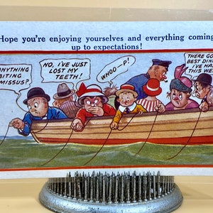 Peut inclure: Une carte postale vintage représentant une illustration humoristique d'un groupe de personnes dans un bateau de pêche. Le texte sur la carte postale dit "J'espère que vous vous amusez bien et que tout se passe comme prévu !"  "Quelque chose mord à l'hameçon, chérie ?"  "Non, j'ai juste perdu mes dents !"  "Wouhou !"  "C'est le meilleur dîner que j'ai eu cette semaine."