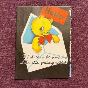 May include: A greeting card with a yellow cat peeking out of an envelope. The envelope has a blue and white design. The card has the text "Hello" and "Wish I could drop in like this greeting will do".