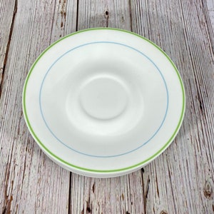 Puede incluir: Plato blanco con borde verde y azul. El plato es de cer&aacute;mica y tiene un acabado liso y brillante.