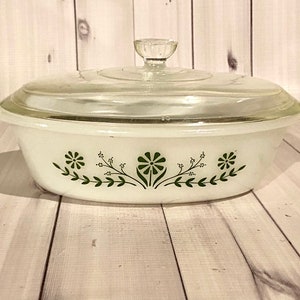 May include: White oval casserole dish with a glass lid. The dish has a green floral design around the rim.