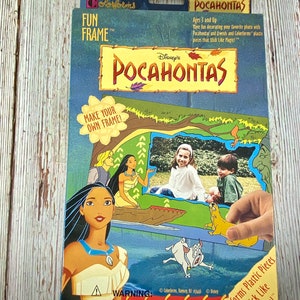 Puede incluir: Una caja para un marco divertido Colorforms de Pocahontas de Disney. La caja presenta una ilustración colorida de Pocahontas, Meeko y otros personajes de la película. La caja también incluye el texto "¡Crea tu propio marco!" y "¡Piezas de plástico Colorforms que se pegan como por arte de magia!"