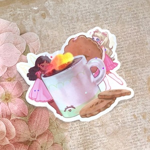 May include: A sticker featuring two fairies, one with brown hair and a pink dress, the other with blonde hair and a pink dress, holding a large mug with a steaming cup of coffee and a cookie. The sticker also includes two cookies on a plate.