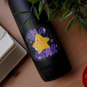 May include: A black water bottle with a sticker that says "I'm a Star" with a yellow star with a face and purple and blue lettering.