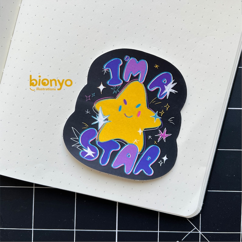May include: A black and white sticker with a yellow star and the text "I'm a Star" in purple and blue lettering. The star has a smiling face and there are small white stars scattered around the sticker.