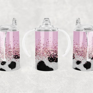 K&ouml;nnte beinhalten: Drei rosa Edelstahl-Trinkbecher mit klaren Deckeln und Griffen. Die Becher haben ein Kuhmuster mit rosa Glitzerakzenten.