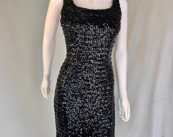 May include: A black sequined sleeveless dress with a square neckline. The dress is fitted and has a short length.