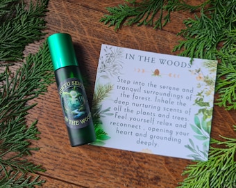 May include: A green roller bottle with a matching cap, labelled "Nintu Sense," featuring a forest scene. A card next to it reads "In The Woods," with text about nature and relaxation. The items are on a wooden surface.