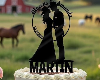 May include: A wedding cake with a decorative topper featuring a silhouette of a couple, with the names "Marcus & Amanda" and the date "10.27.2022". The cake is on a wooden table, with a rustic outdoor setting in the background.