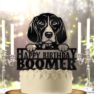 May include: Black and white cake topper featuring a dog peeking over a sign that says "Happy Birthday Boomer".