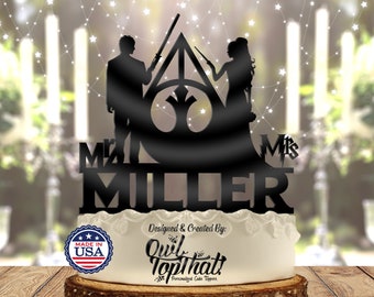 May include: Black silhouette cake topper featuring a bride and groom holding wands in front of the Hogwarts crest. The topper says "Mr. & Mrs. MILLER" and "Made in USA".